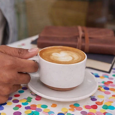 Peet’s 官方生日福利照片，一杯拉花咖啡摆在彩纸旁