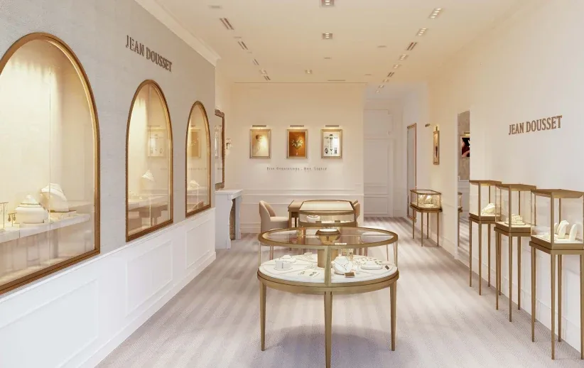 浅色调的珠宝店内：拱形玻璃橱窗、圆形展柜和墙上的 JEAN DOUSSET 字样
